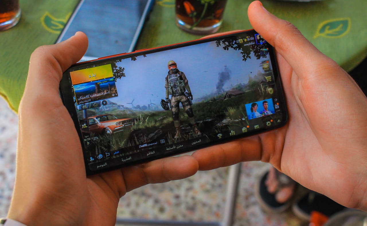 From above crop anonymous male playing captivating video game on contemporary mobile phone near table on terrace